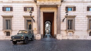 A historic building with a cobblestone street and a green military vehicle parked in front. - Palazzo Borghese, a Burghesius home (Roma)