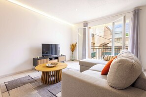 Un salon moderne avec un canapé, un téléviseur et une table à manger.