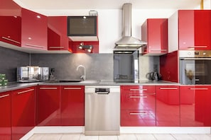 Une cuisine moderne avec des meubles de rangement rouges, des appareils électroménagers en acier inoxydable et un lave-vaisselle.