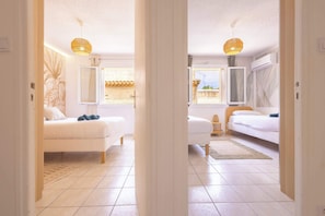 A room with two beds, a large window, and a view of the outside.