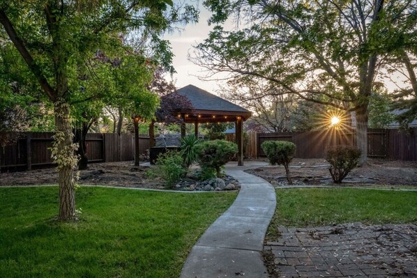A backyard with a gazebo, a pathway, and a wooden fence.