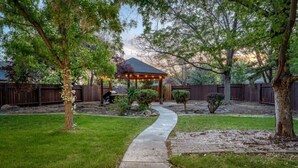 A backyard with a gazebo, a paved walkway, and a wooden fence. - High Desert Haven Pool Table Garden Oasis & Gazebo (Sparks)