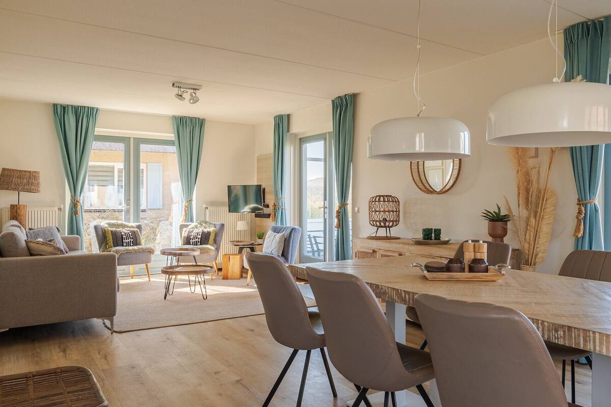 A modern living room with a dining area, large windows, and a view of the outside.