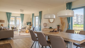 Una sala de estar moderna con comedor, ventanas grandes y vistas a edificios.