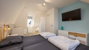 Ein Schlafzimmer mit zwei Betten, einem Fernseher und einer Heizung.