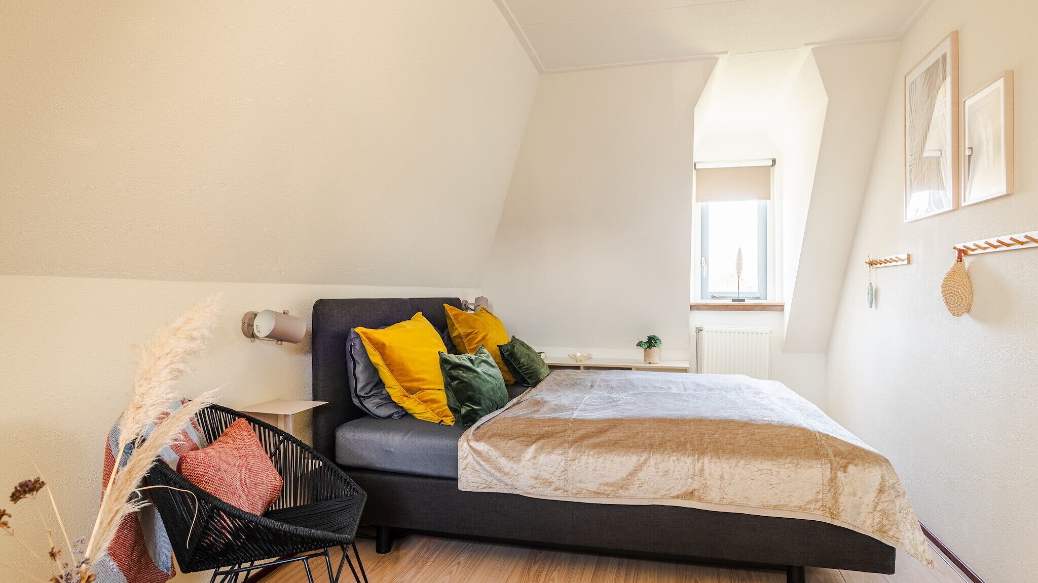 A bedroom with a bed, a chair, a bedside table, a window, and a radiator.