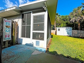 A residential property with a front door, a small porch, a well-maintained lawn, and a wooden fence.