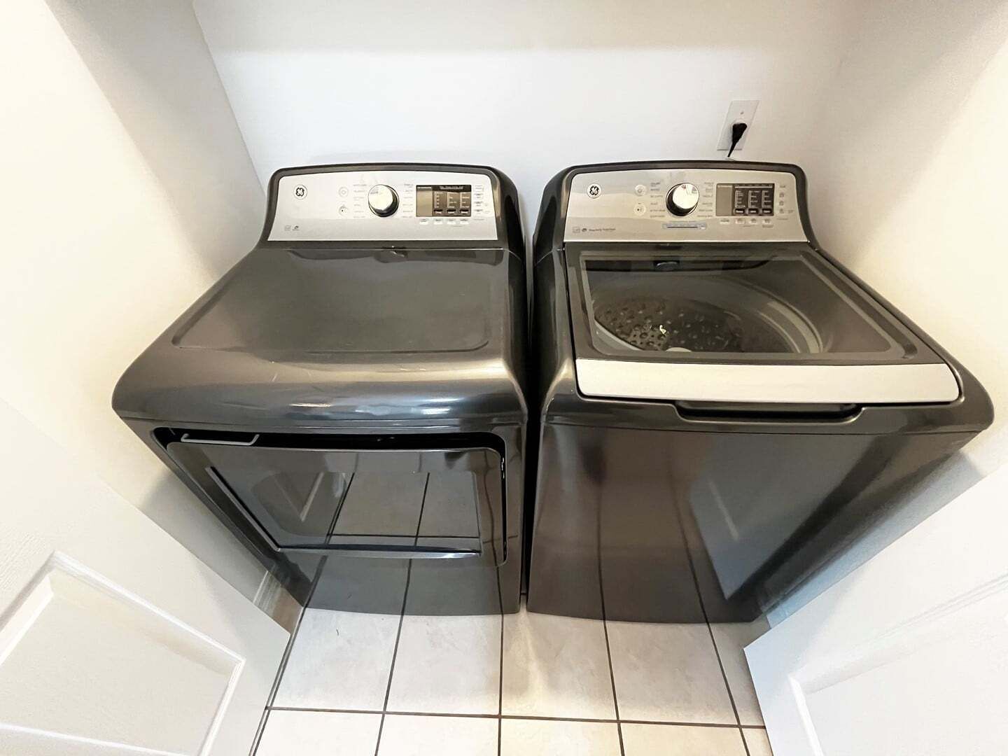 A laundry room with two front-loading washing machines and a tiled floor.
