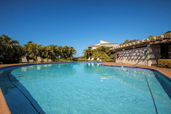 Relax by the pool surrounded by lush greenery and lounge chairs.