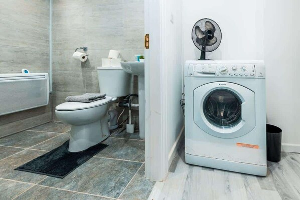 Ein kleines Badezimmer mit Toilette, Waschbecken und Waschmaschine.
