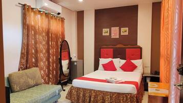 A hotel room with a bed, a sofa, a mirror, and a small table.