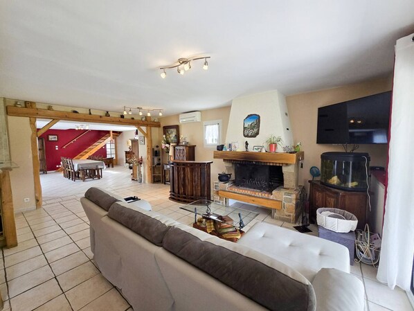 A spacious living room with a fireplace, a television, and a dining area with a staircase.
