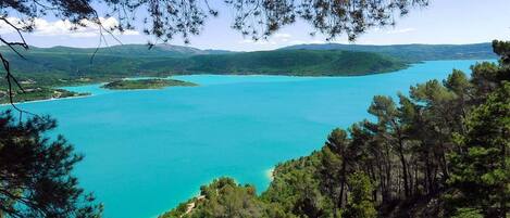 A coastal landscape with turquoise waters, surrounded by dense green forests and hills.