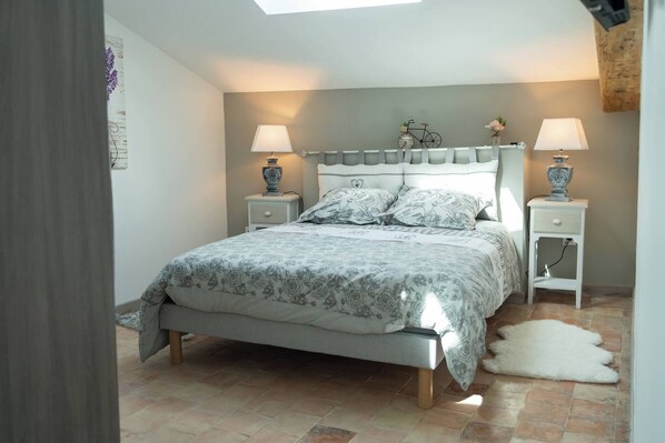 Un dormitorio con cama, dos mesitas de noche con lámparas, una decoración de bicicleta en la pared y una alfombra de piel blanca en el suelo.