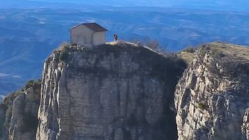 A small building on a cliff edge with a vast landscape in the background.