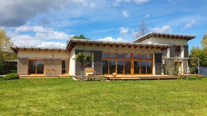 Une maison moderne à deux étages, dotée de grandes fenêtres, d’un patio et d’une pelouse bien entretenue.