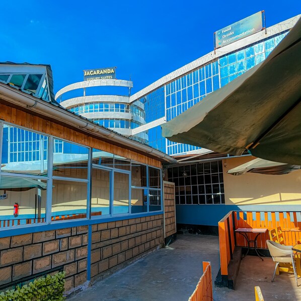 Un edificio con un cartello che indica "JACARANDA LUXURY SUITES" e un cartello che indica "Cibo, bevande, alloggio".