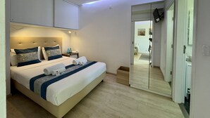 A bedroom with a bed, bedside tables, a mirror, and a television. - Vilamoura Marina View 2 by Homing (Loulé)