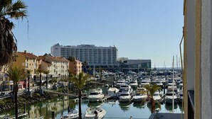 A marina with numerous boats docked, a hotel with a modern facade, and a clear blue sky. - Vilamoura Marina View 2 by Homing (Loulé)