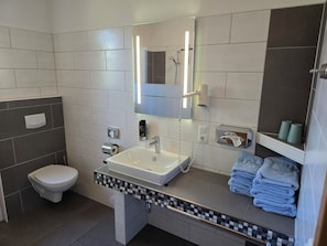 Une salle de bain moderne équipée de toilettes, d’un lavabo et d’un porte-serviettes.