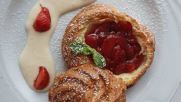 Um prato de sobremesa com um pastel, um pouco de creme e uma morango.