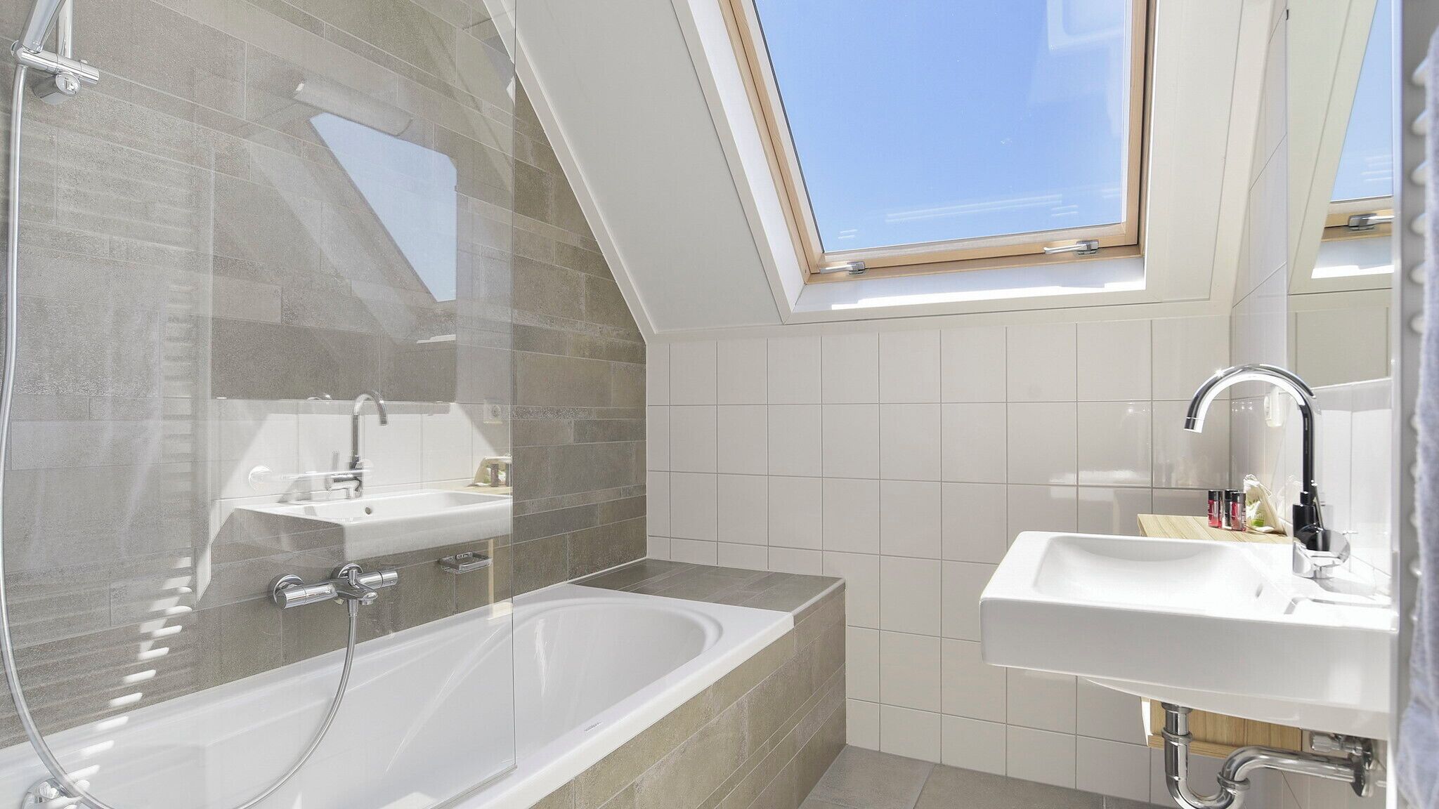 Ein modernes Badezimmer mit einem Oberlicht, einer freistehenden Badewanne und einem Waschtisch.