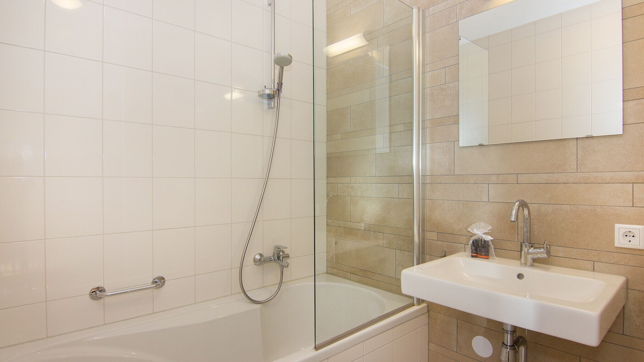 Une salle de bain moderne avec une douche à parois de verre, une baignoire blanche et un lavabo surmonté d’un miroir.