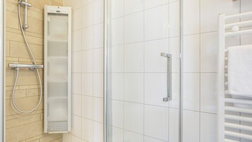 A shower area with a glass door, a towel rack, and a control panel.