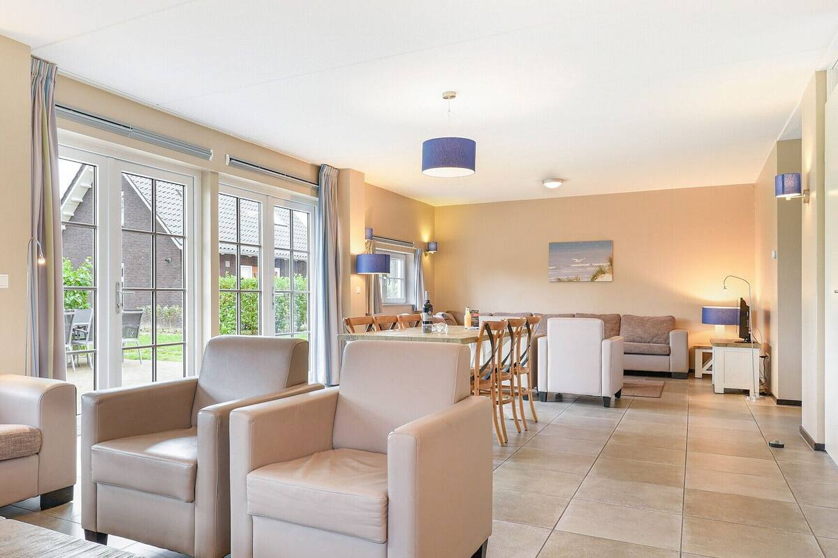 A spacious living area with a dining table, comfortable seating, and large windows offering a view of the outdoors.