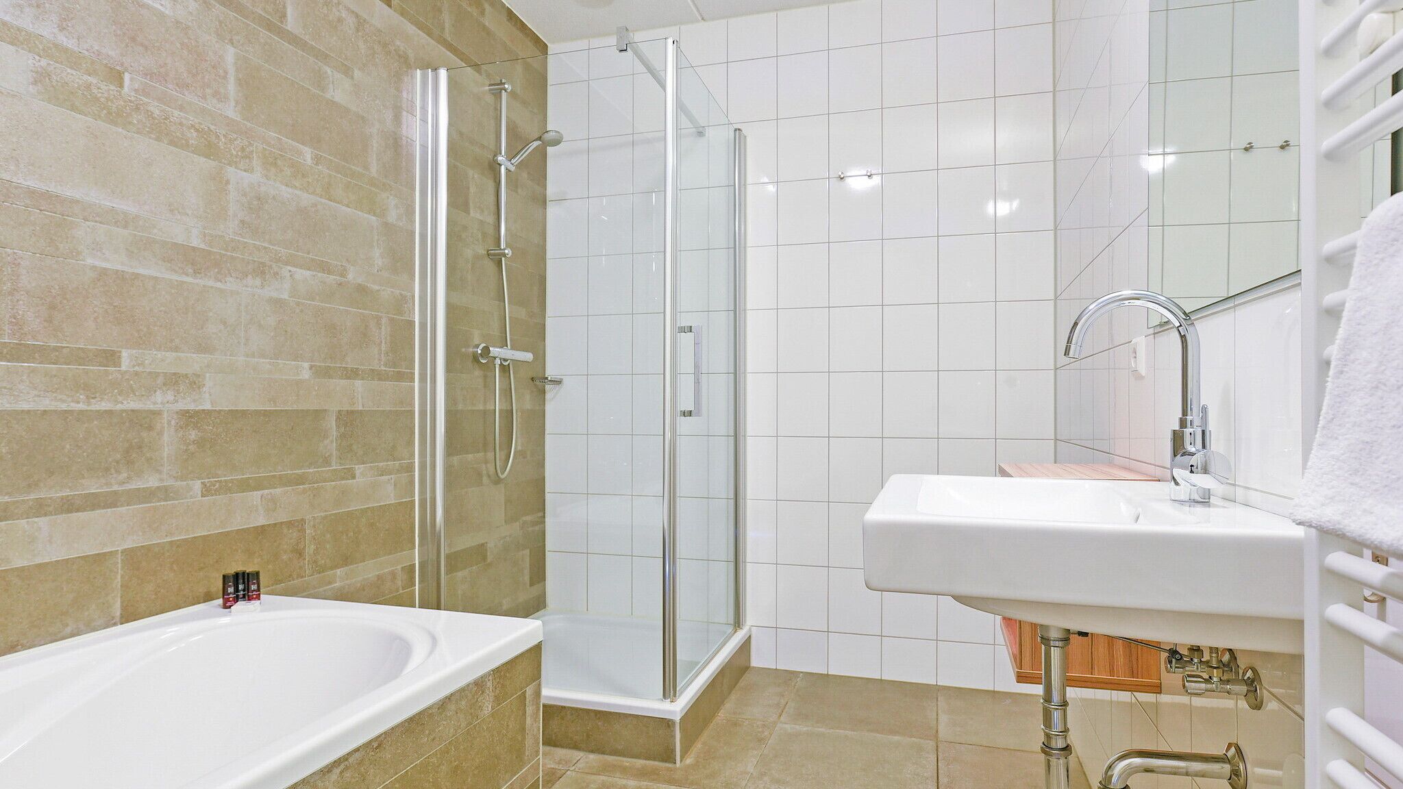 Ein modernes Badezimmer mit Badewanne, einer Glaskabine für die Dusche und einem Waschbecken mit Spiegel.