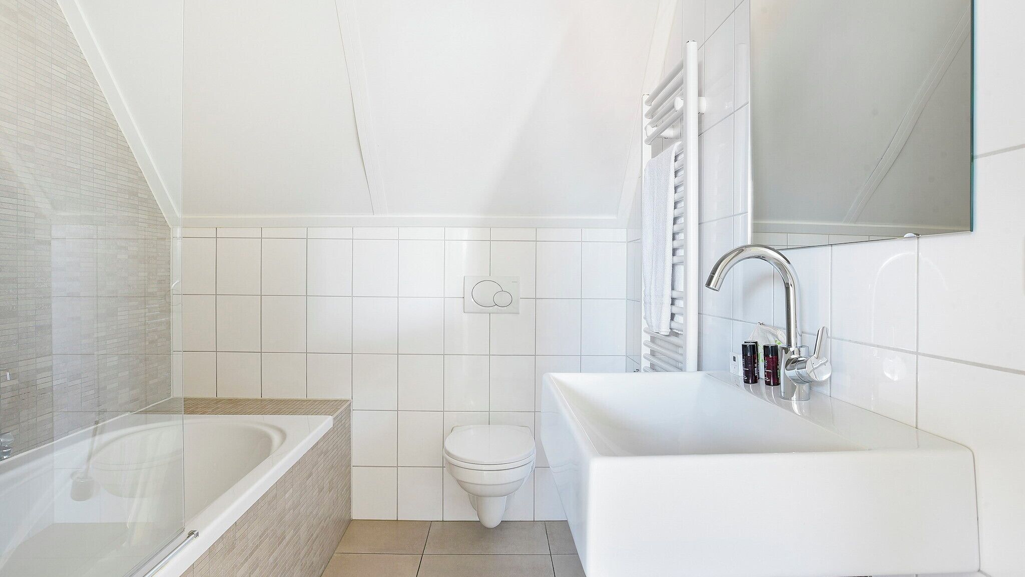 A modern bathroom with a glass-enclosed bathtub, a white sink, and a toilet.