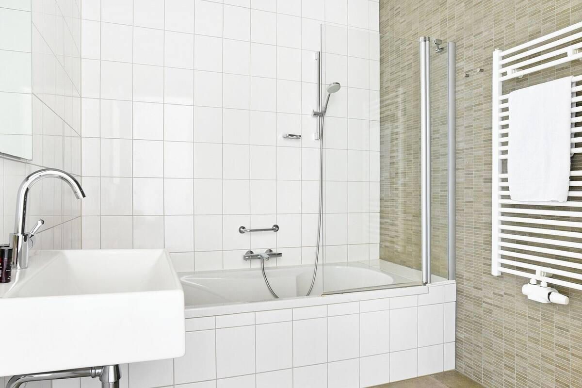 A modern bathroom with a white sink, a glass-enclosed shower, and a towel rack.