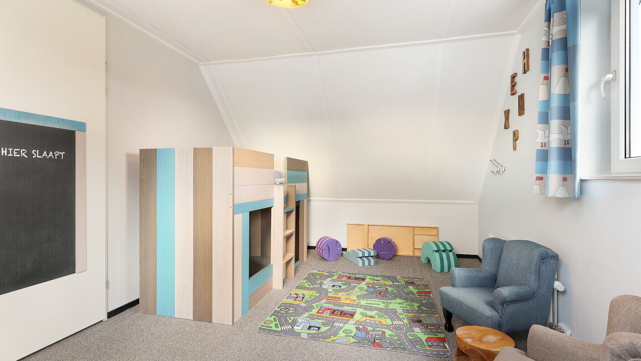 A child's playroom with a chalkboard, wooden play structures, and a colorful mat.