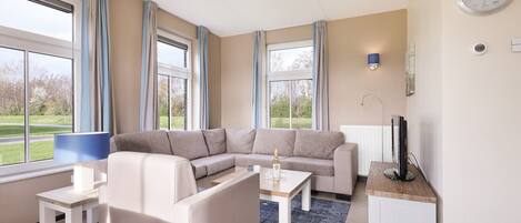 A modern living room with a sectional sofa, a coffee table, a TV, and a fireplace.