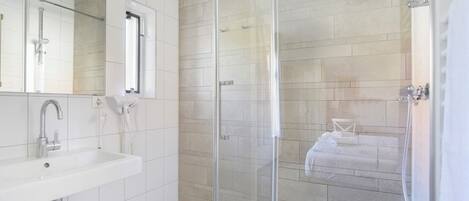 Un baño moderno con cabina de ducha de vidrio, un lavabo blanco y un espejo.