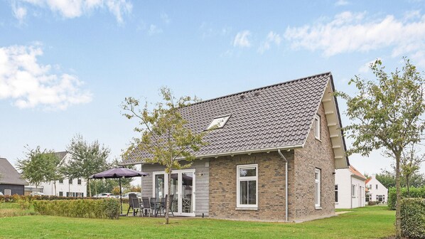 A single-story house with a sloped roof, a small porch with outdoor seating, and a well-maintained lawn. - Dormio Strand Resort Nieuwvliet-bad (Nieuwvliet)