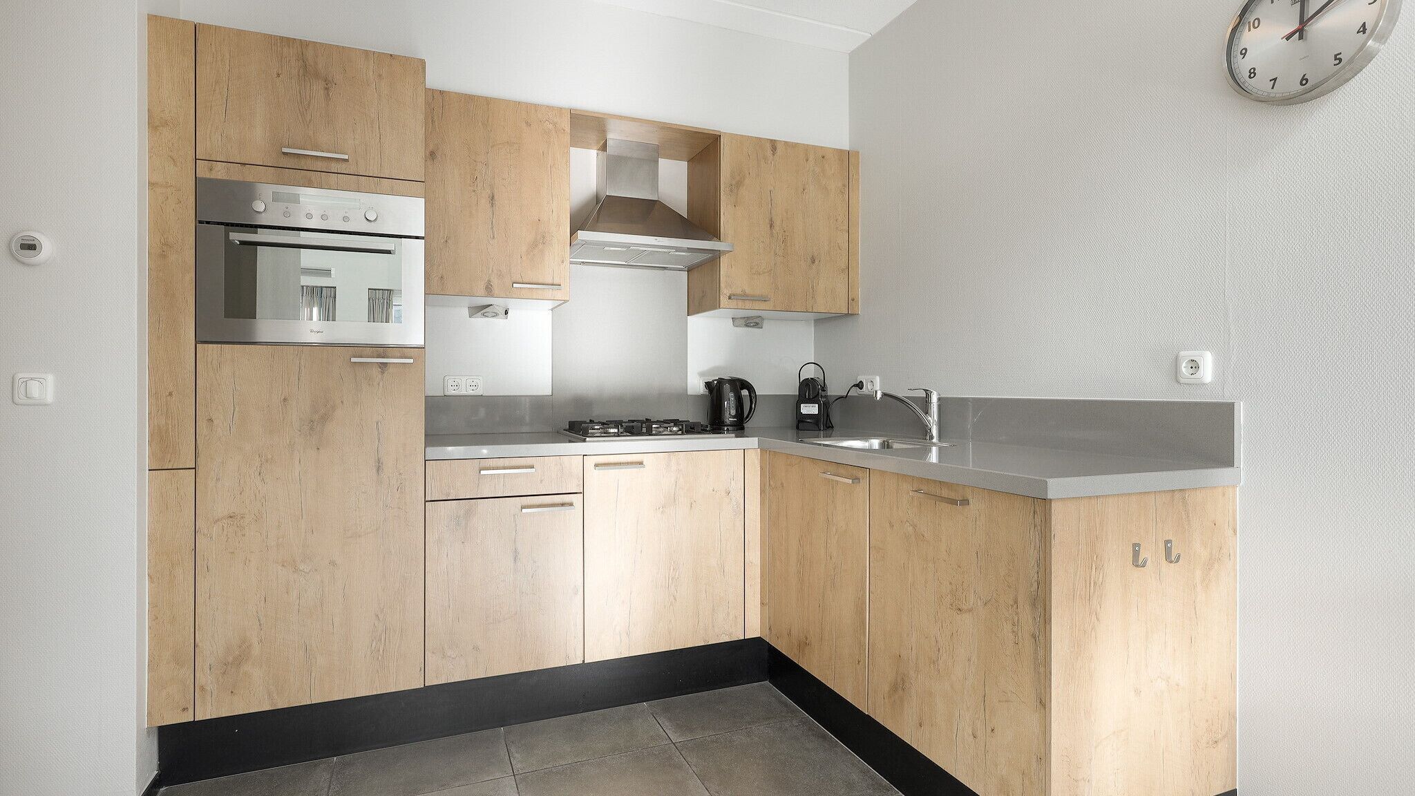 A modern kitchen with wooden cabinets, a stainless steel oven, a gas stove, and a sink.