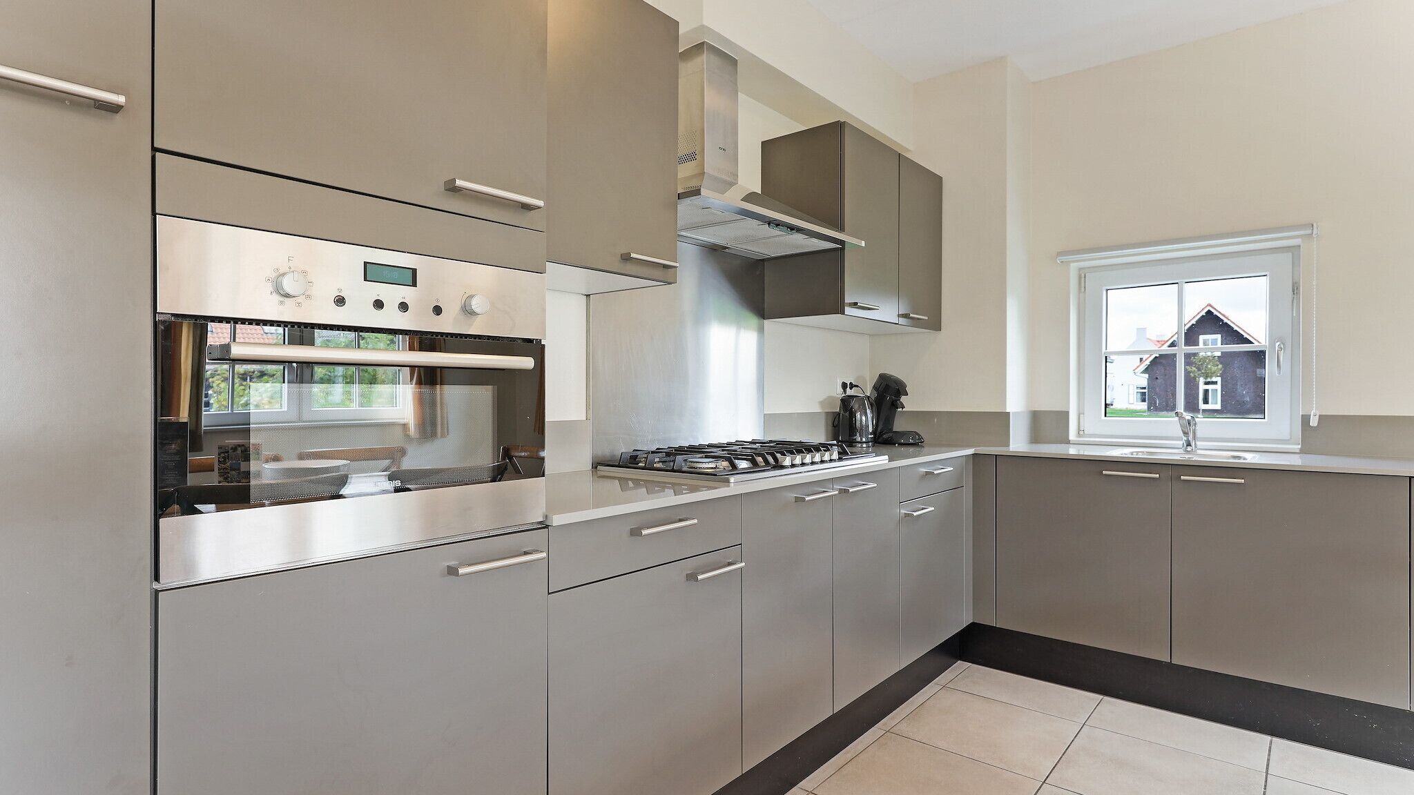 A modern kitchen with stainless steel appliances, a gas stove, and a window providing a view of the outside.