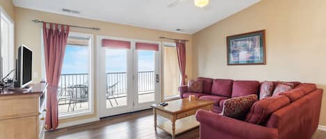 A living room with a red sofa, a wooden coffee table, and a ceiling fan.