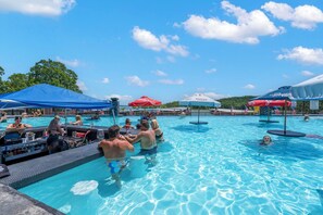 A swimming pool area with multiple pools, umbrellas, and a bar area.