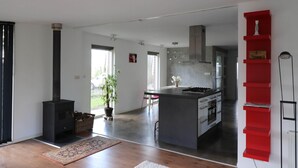 A modern kitchen with a central island, a built-in stove, and a red shelving unit. - Vacation home for 6 people in the Drents Friese Wold (Zorgvlied)
