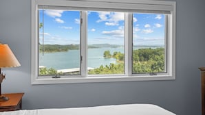 A room with a large window offering a view of a lake and greenery. - Tranquil Lakeview: Condo with Boat Rentals (Branson)