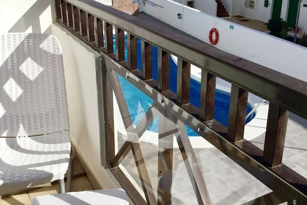 Un espace piscine avec une rambarde en métal, un mur blanc et une bouée de sauvetage.