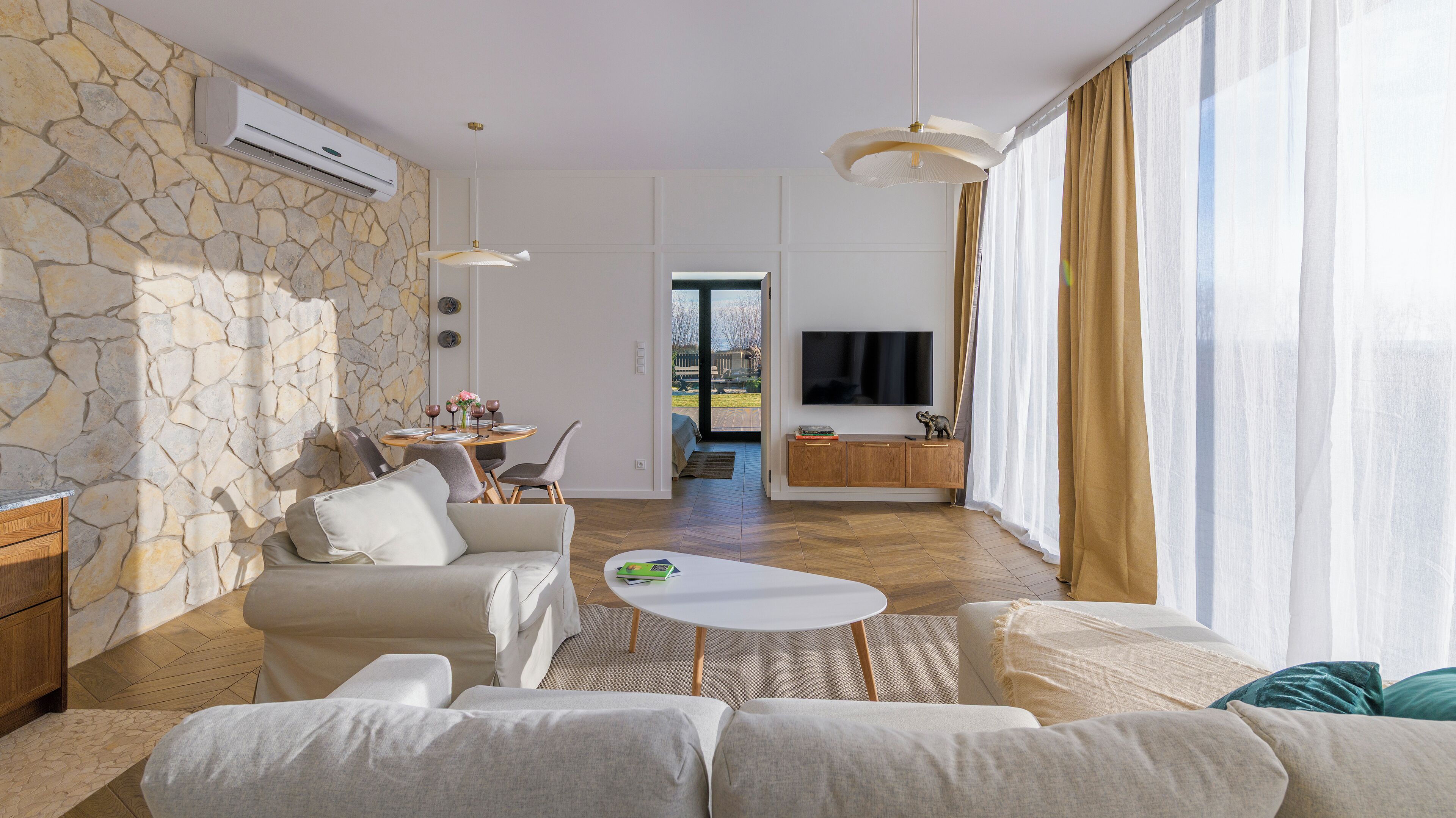 A modern living room with a stone wall, a sofa, a coffee table, and a TV in the background.