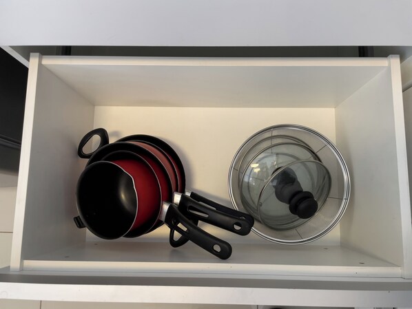 A kitchen drawer with pots, pans, and a glass lid. - ADD Nova Berrini (Sao Paulo)