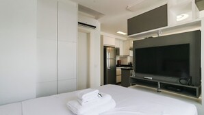 Ein Hotelzimmer mit Bett, Fernseher, Küchenzeile und Bad.