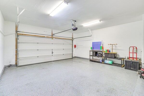 A clean, well-lit garage with a large garage door, overhead lighting, and organized storage shelves.
