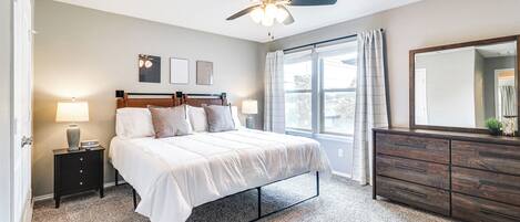 A bedroom with a bed, nightstand, dresser, and ceiling fan.