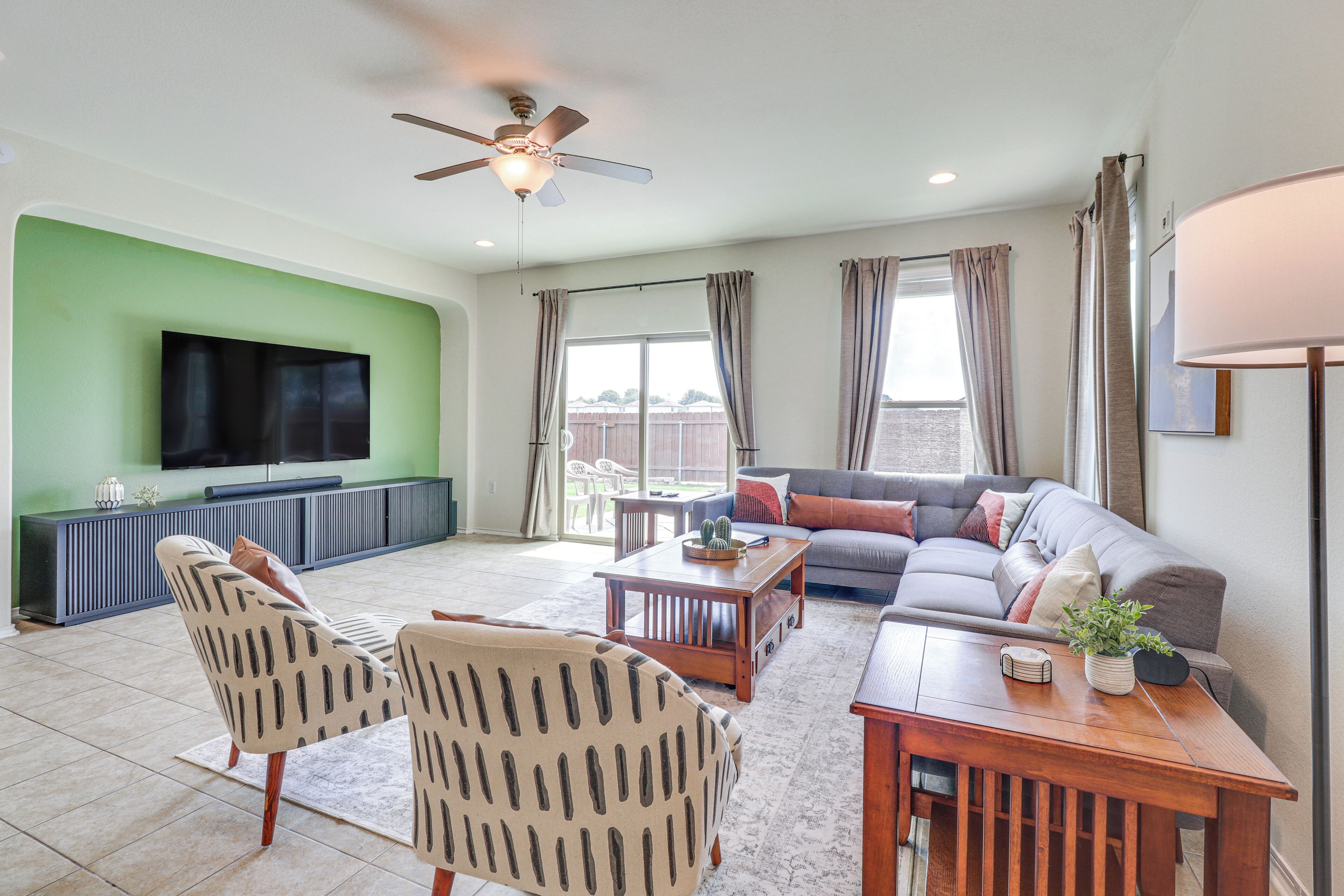 A living room with a sofa, chairs, a coffee table, a TV, and a ceiling fan.