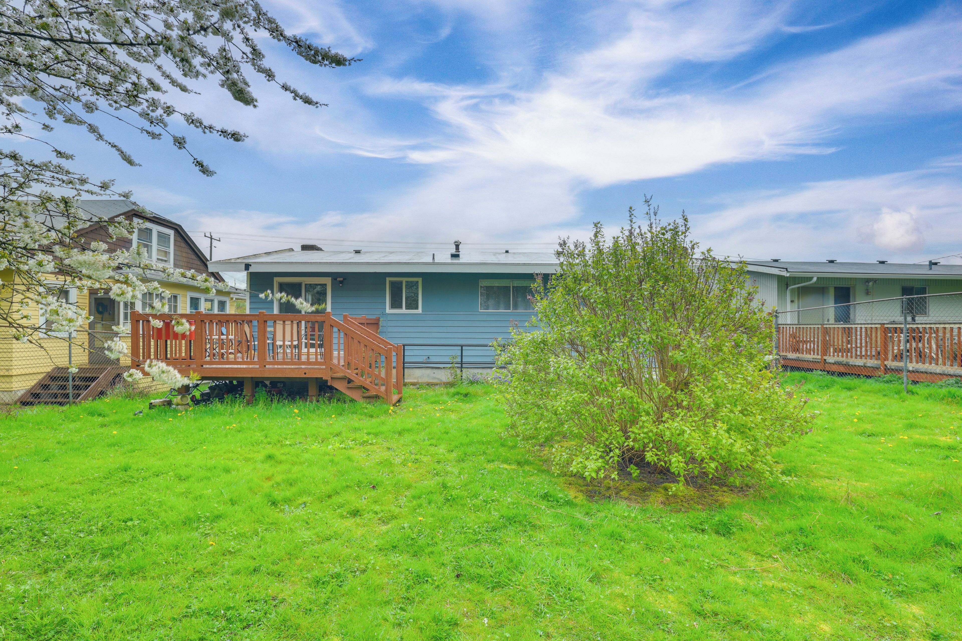 A residential property with a blue house, a wooden deck, and a small garden.